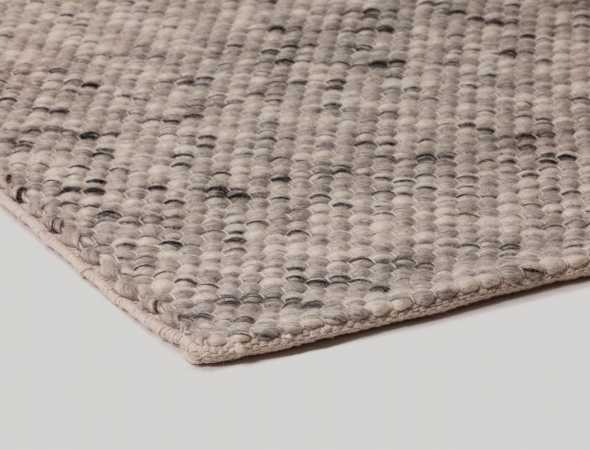שטיח העשוי מחוטי צמר המשלבים צבעים לבנים, שחורים ואפורים בפיזור אקראי
