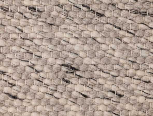 שטיח העשוי מחוטי צמר המשלבים צבעים לבנים, שחורים ואפורים בפיזור אקראי